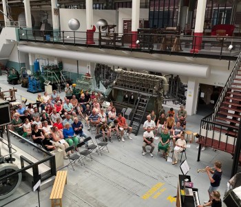 museum gevuld met bezoekers luisterend naar optreden