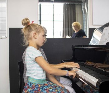Een meisje dat op een zwarte piano speelt
