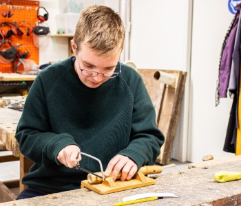 Persoon zaagt aan een bamboestuk om een bamboefluit te maken in een werkplaats.